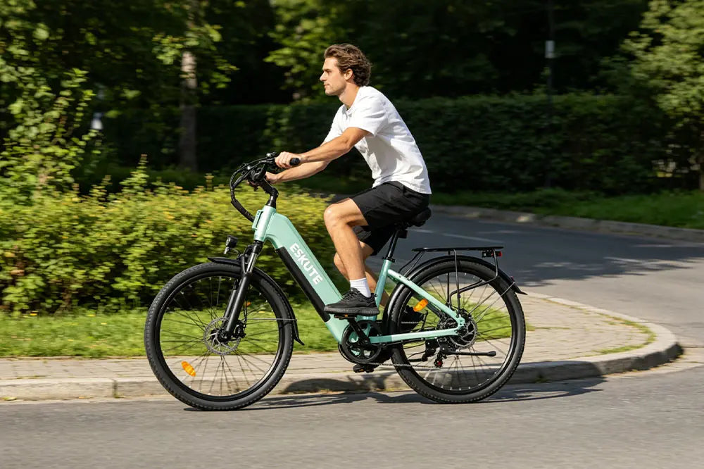 ESKUTE C202 city e-bike in use: A man riding the mint-green ESKUTE commuter bike through a sunlit neighborhood, highlighting its comfortable step-through frame and smooth performance