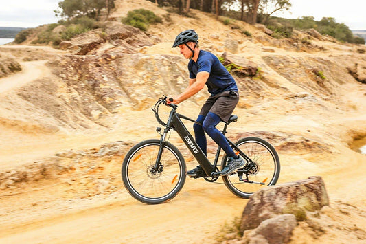 ESKUTE electric mountain bike being ridden on rocky off-road trail by helmeted rider