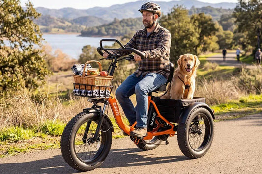 Helmeted man in plaid shirt riding orange ESKUTE fat tire three-wheel electric tricycle, golden retriever dog sitting in rear cargo basket, picnic basket with food in front basket, scenic lakeside mountain trail, family pet friendly e-bike