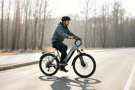 Daytime lifestyle shot of lightweight urban electric bicycle with rear rack, helmeted rider on empty paved road